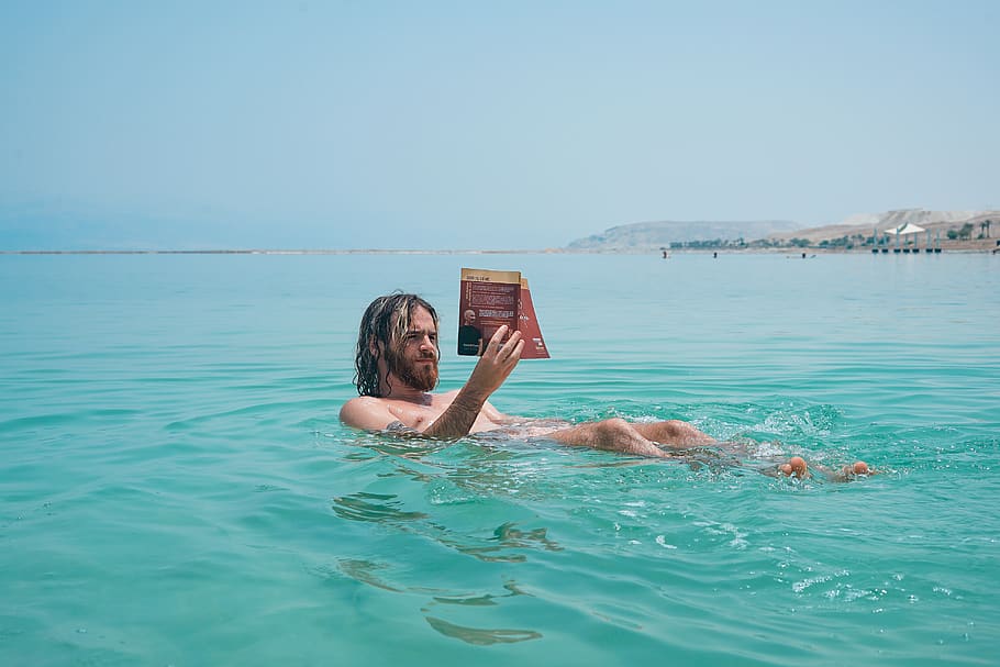 man floating on body of water while reading book, the dead sea