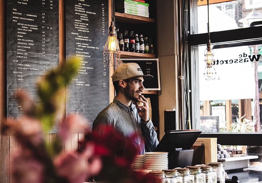 man wearing brown cap in across menu board, person, human, restaurant