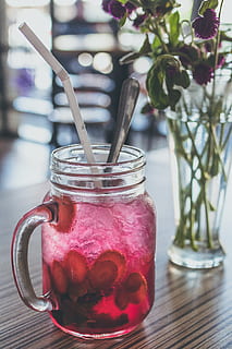 Red Beverage-filled Clear Glass Mason Mug With Straw Beside Purple Flowers in Vase HD wallpaper