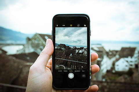Person Holding Black Smartphone Taking a Picture of Brown House at Daytime HD wallpaper