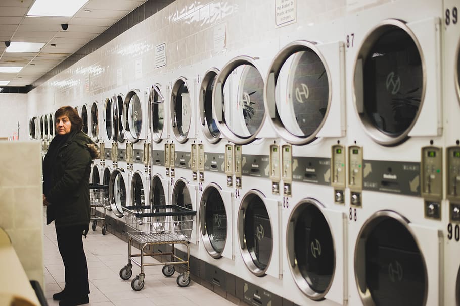woman in black jacket near washers, laundromat, washing machine