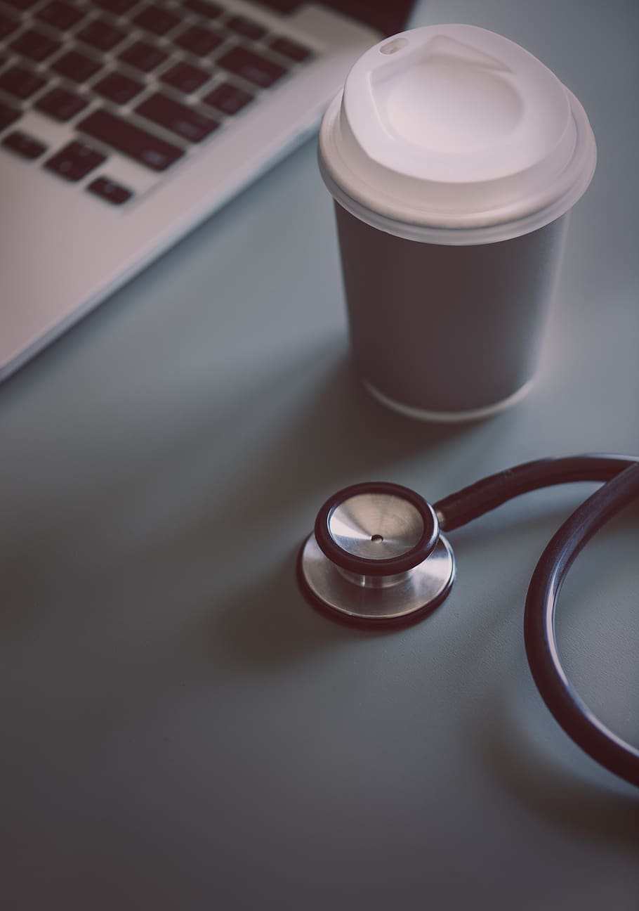 Gray and Black Stethoscope Beside Disposable Cup and Macbook Pro HD wallpaper