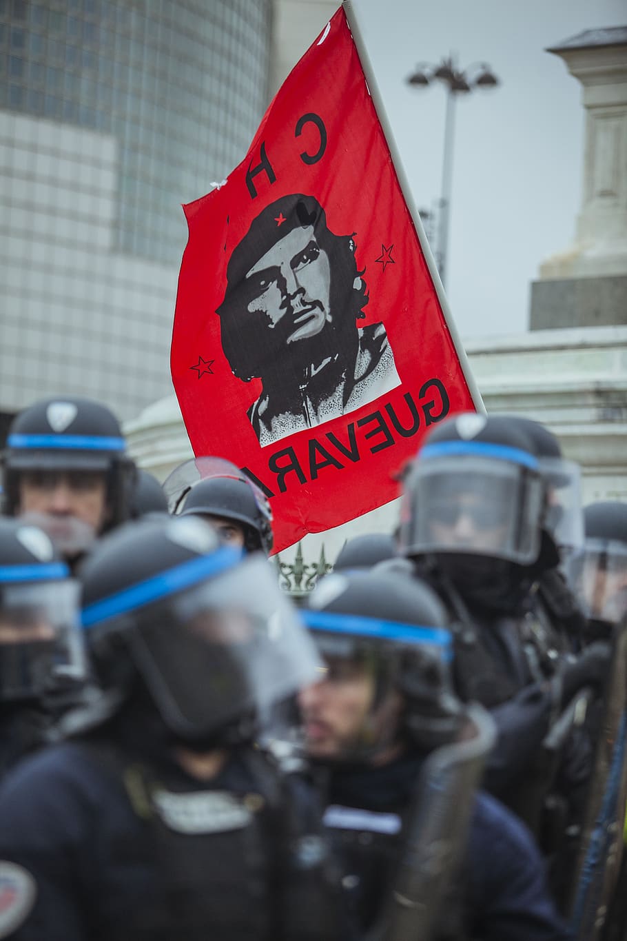 red Che Guevara flag near group of police during daytime, communication