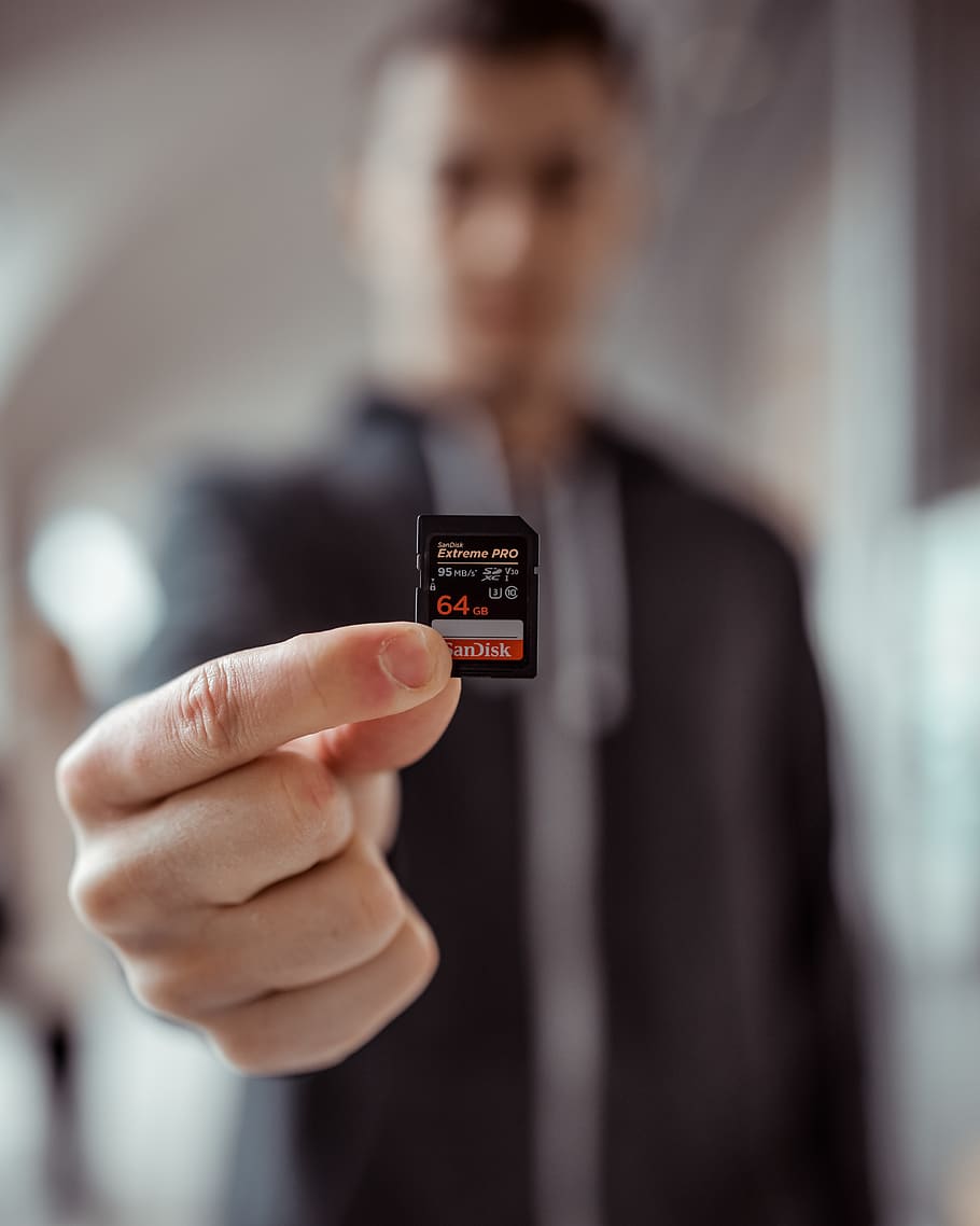 Person Holding Sandisk 64gb Microsd Adapter, blur, close-up, depth of field