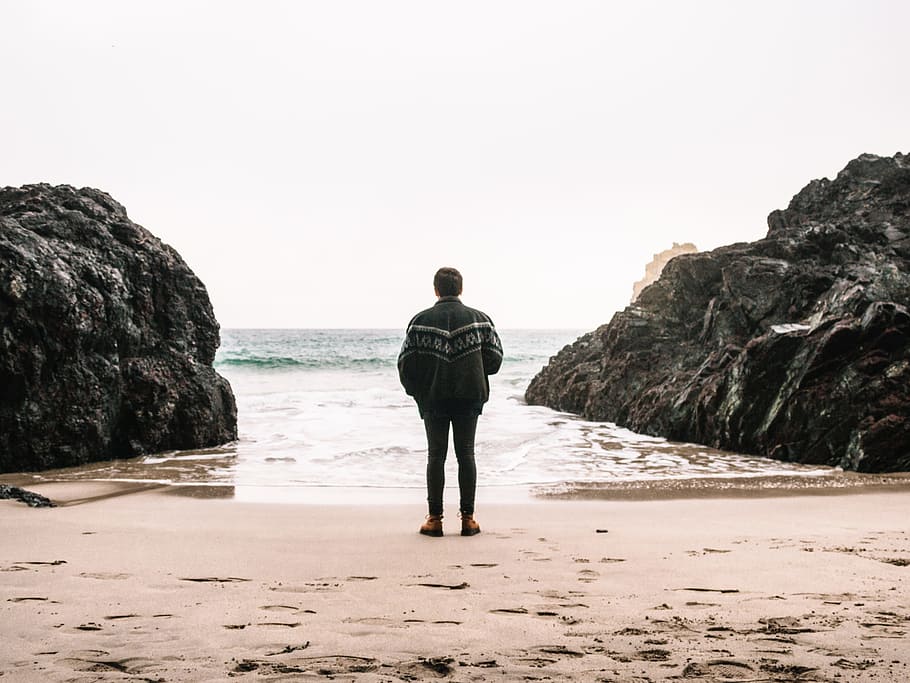 man, guy, back, rock, formation, sea, ocean, sand, jacket, sky HD wallpaper