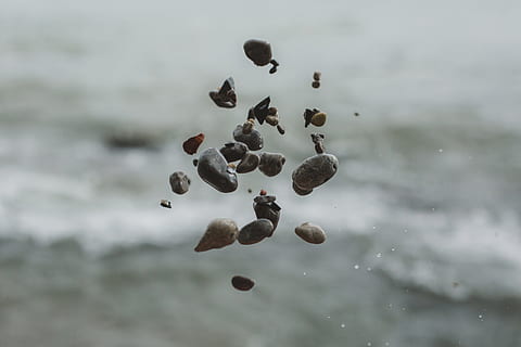 Close up of pebble stones floating in the air after being thrown with blurred background HD wallpaper