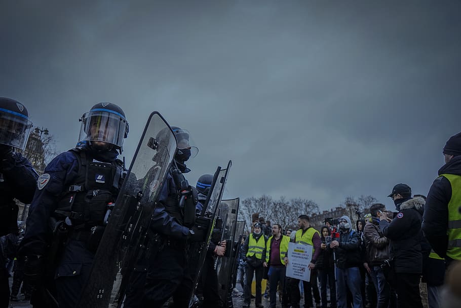 anti-riot police near line of people under gray skies, apparel