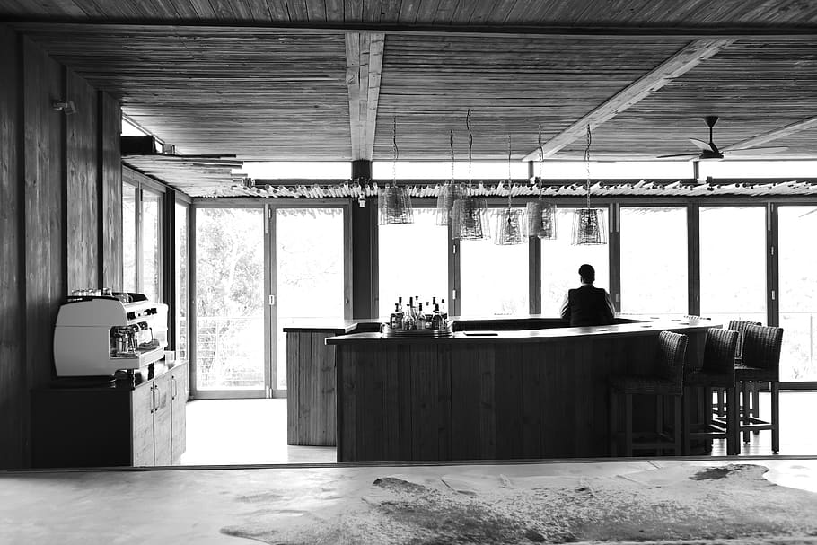 man standing inside bar counter in grayscale photo, human, person