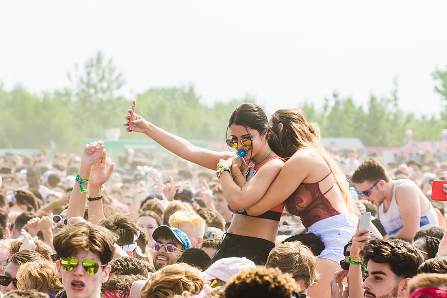 Two Women Embracing Surrounded by Crowd, arms raised, best friends