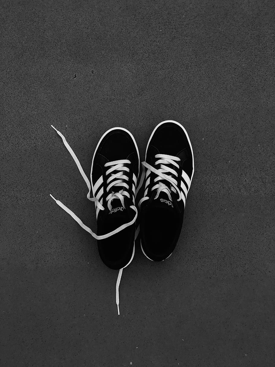 Pair of Black-and-white Adidas Sneakers on Grey Floor, black and white