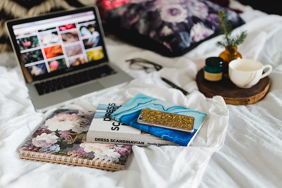 Bed full of pillows and notebooks with Apple gadgets, magazines HD wallpaper