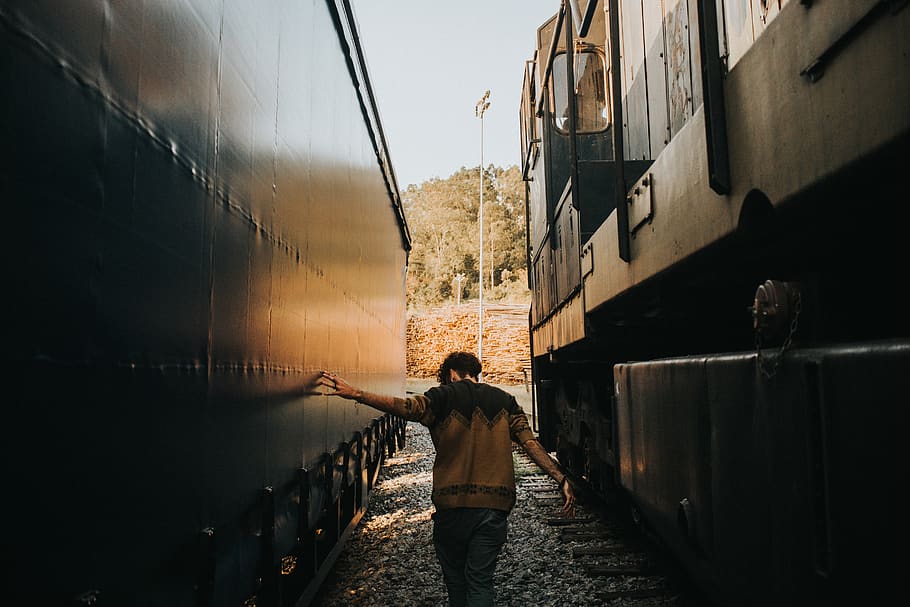 Man Walking in Between Trains, back view, daylight, guy, huge HD wallpaper