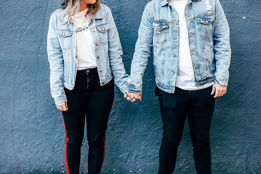 Two Person Standing and Holding Their Hands Beside Blue Wall HD wallpaper