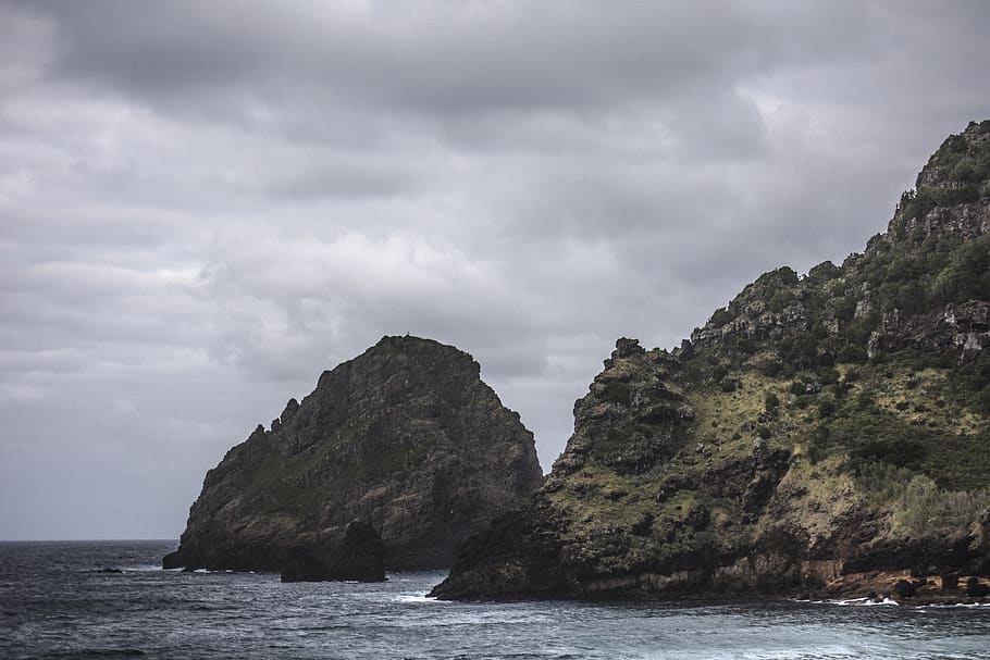 Brown Rock Formation on Body of Water Under Gray Clouds, coast HD wallpaper