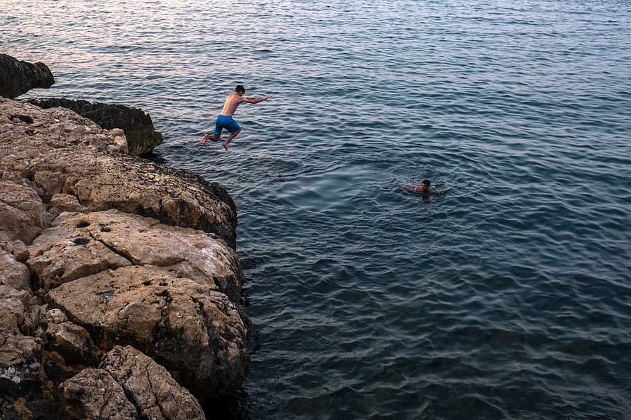 man jumping on cliff, water, rock - object, solid, real people HD wallpaper