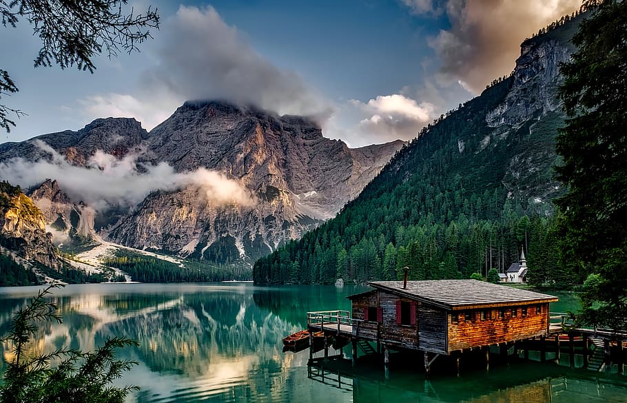 Mirror Lake Reflecting Wooden House in Middle of Lake Overlooking Mountain Ranges