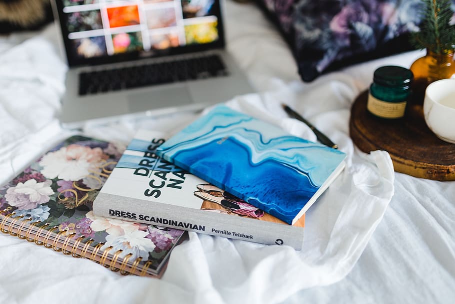 Bed full of pillows and notebooks with Apple gadgets, magazines HD wallpaper