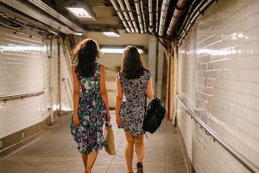 Two Women Carrying Bags While Walking in Tunnel, back view, commuters HD wallpaper