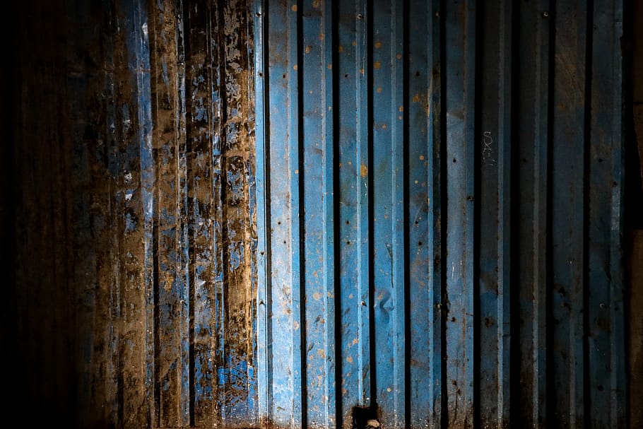 corrugated teal metal panel, wall, wood, plant, door, brick, rust