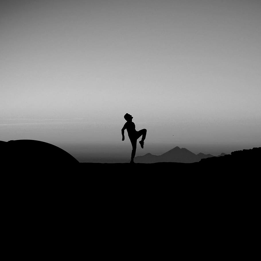 silhouette photography of man standing with one leg on ground HD wallpaper