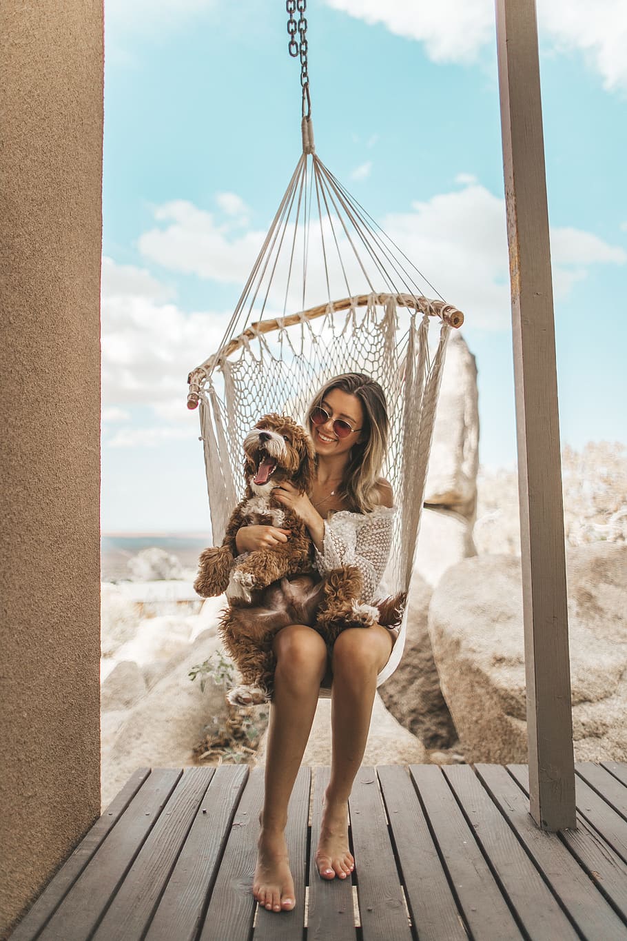 woman sitting on hammock with plush toy, dog, swing, coast, rock