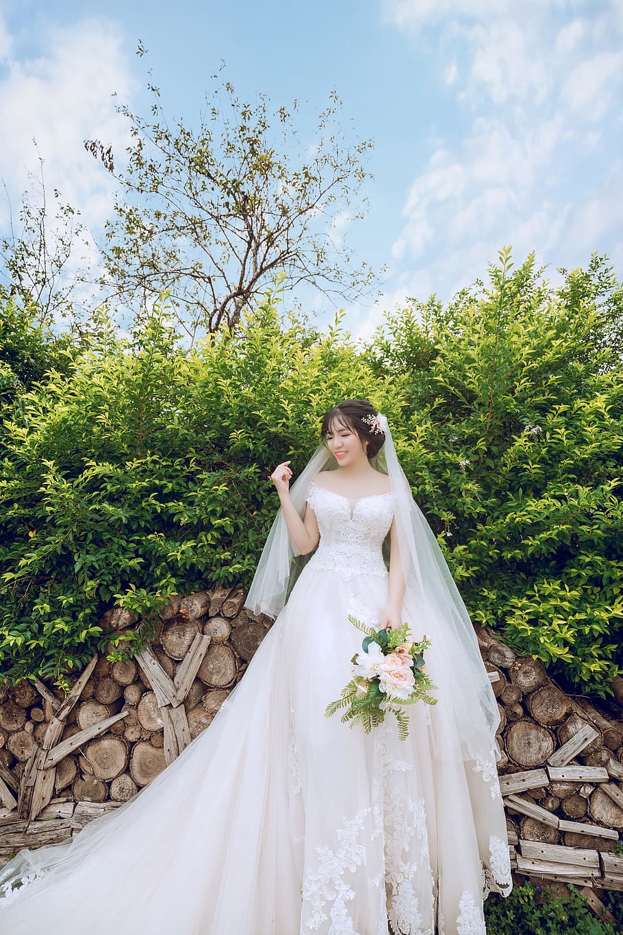 Bride Standing in Front Green Leaf Plant While Holding Bouquet