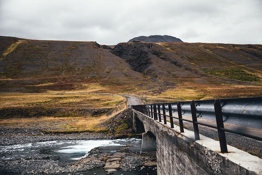 A bridge over a fresh water stream surrounded by moss grown mountains HD wallpaper