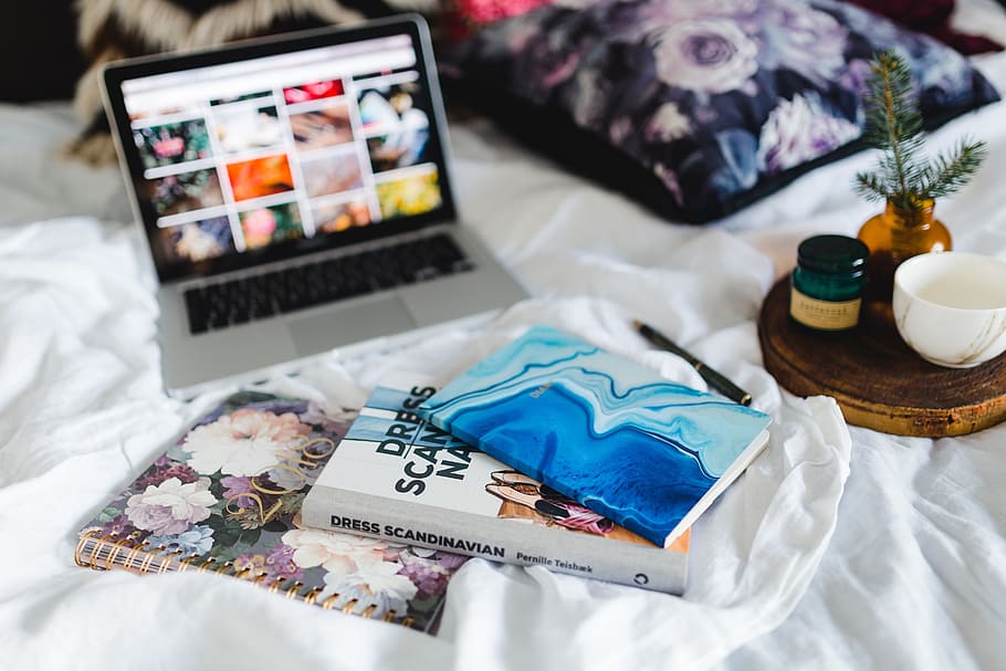 Bed full of pillows and notebooks with Apple gadgets, magazines HD wallpaper