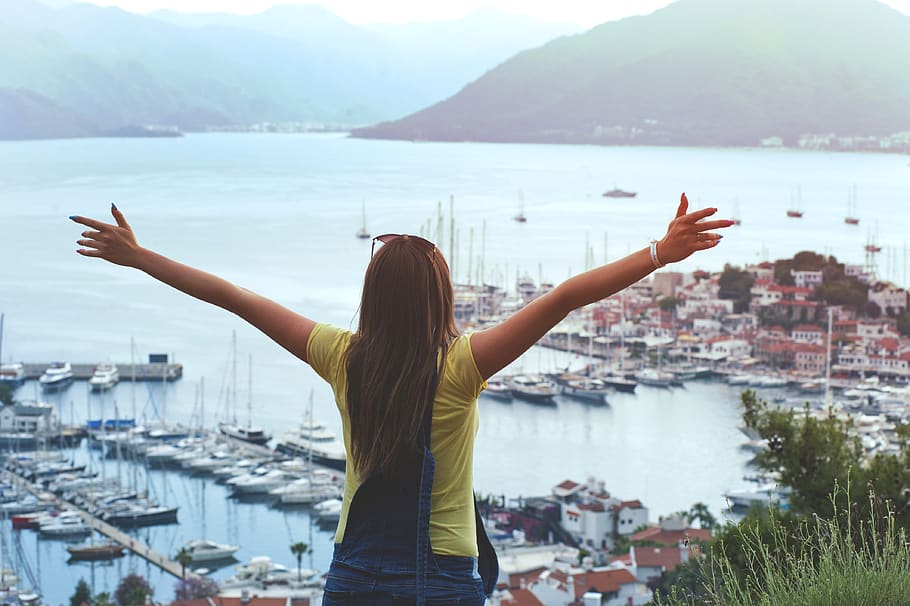Woman Raising Her Hands Facing Cityscape Near Body of Water, back view HD wallpaper