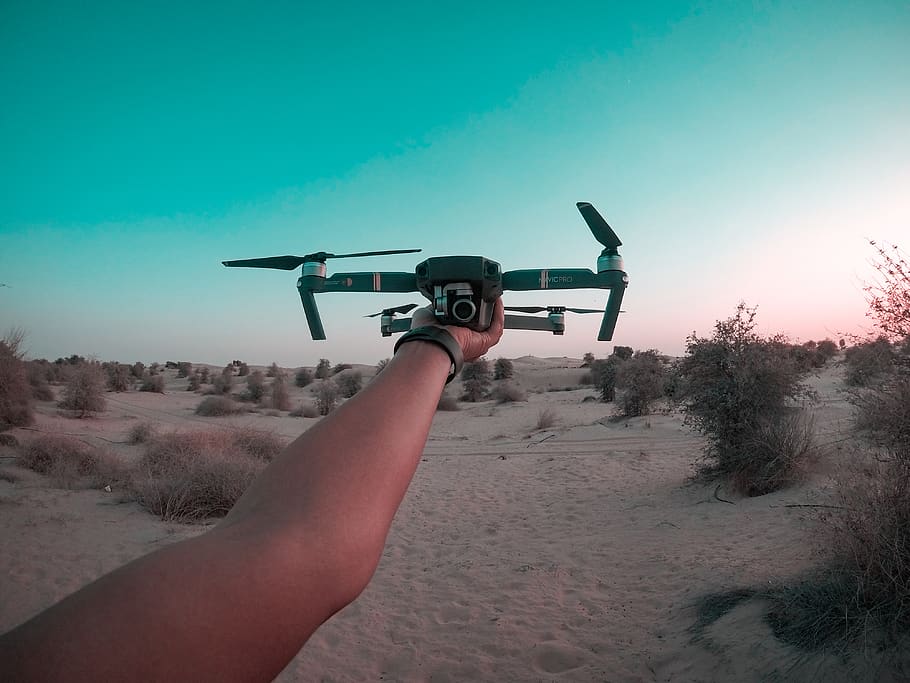 Person Holding Drone, daylight, desert, drone cam, hand, landscape HD wallpaper