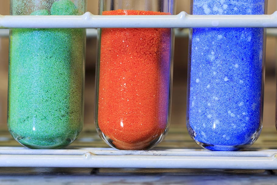 Different colored inorganic chemical salts used in a chemistry lab.