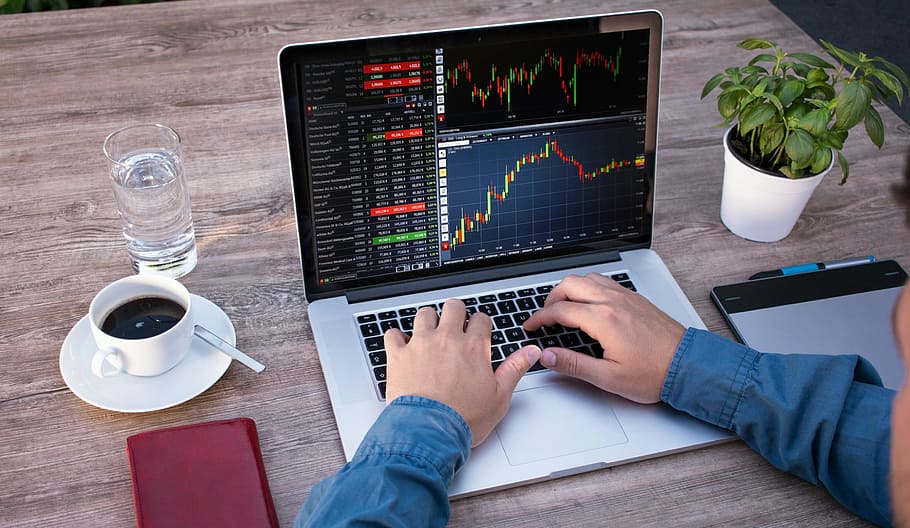 Photo illustration of person working at a laptop computer, which displays screen full of stock market data