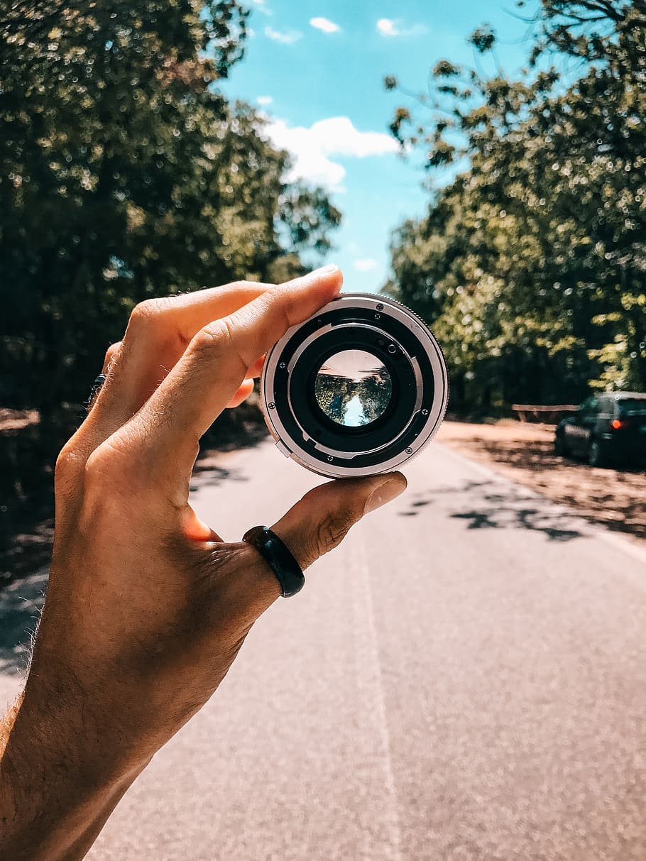 Person Holding Camera Lens in the Middle of Street Under Blue Sky HD wallpaper