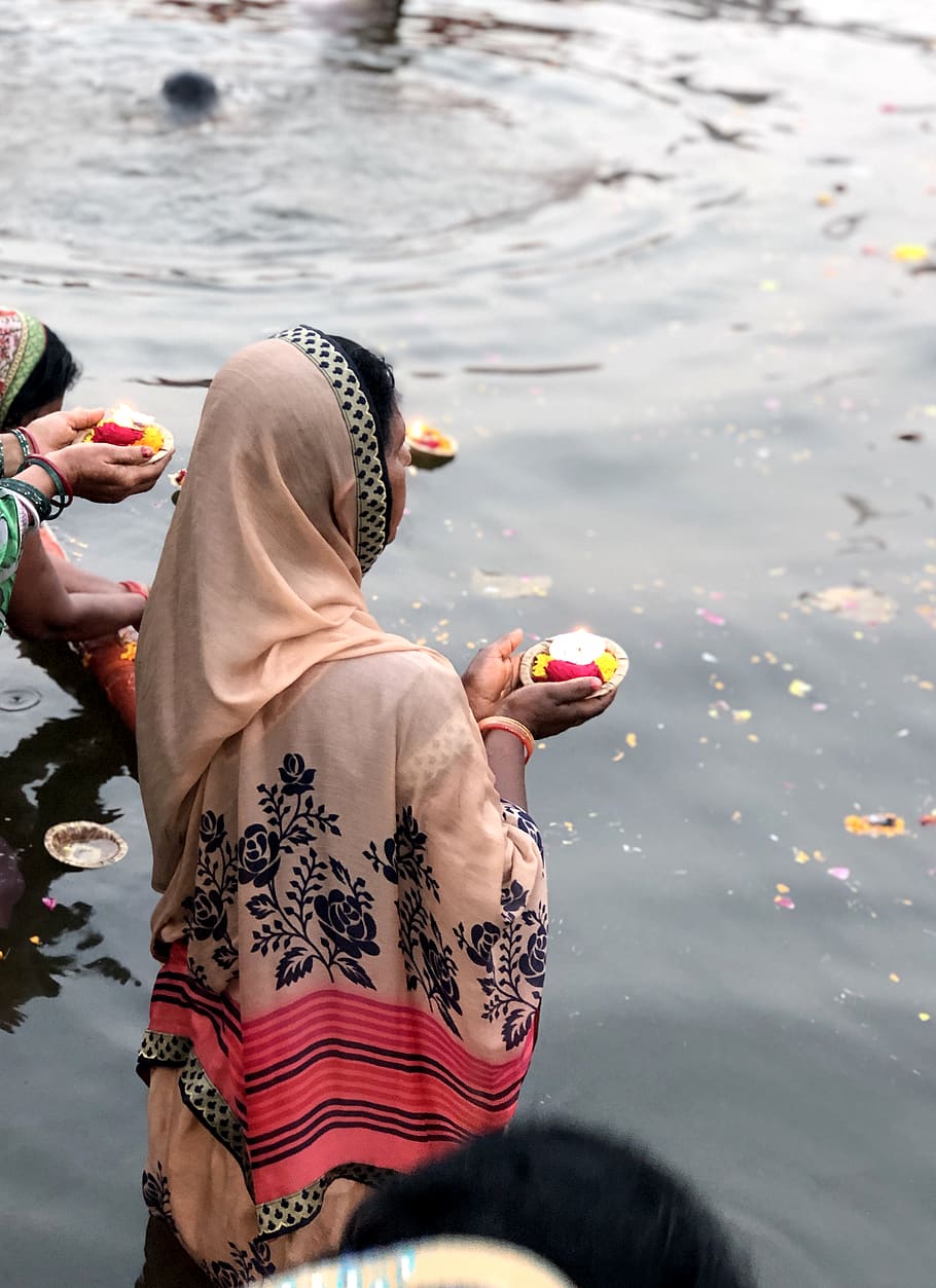 woman wearing pink hijab holding candle while standing on body of water