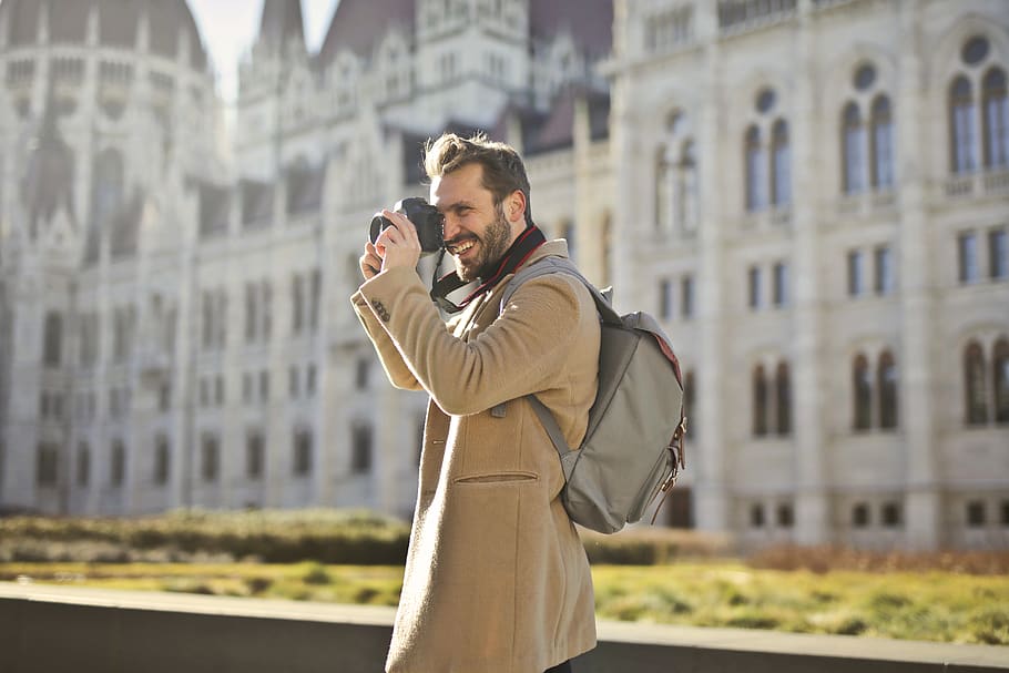 Man Holding and Capturing Images Around Him, architecture, backpack