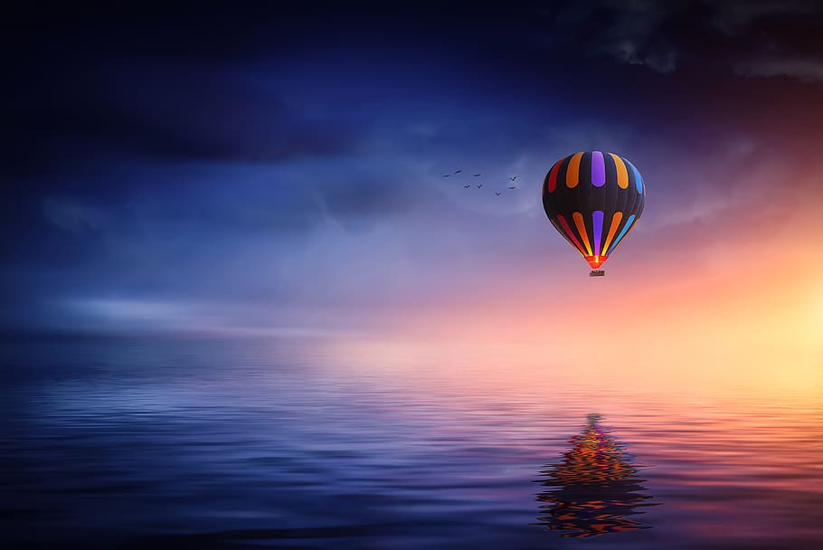 Multicolored Hot Air Balloon over Calm Sea, adventure, backlit