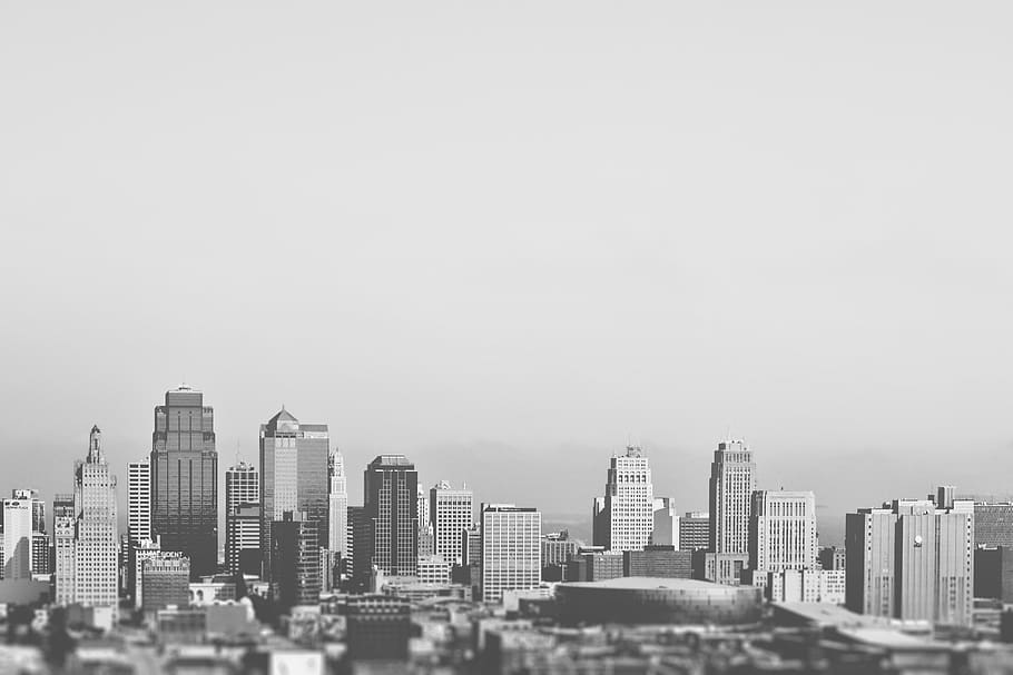 This black and white picture shows the downtown and business district of a typical american city. Some medium sized sky scrapers, some low-rise buildings and a stadium are visible. The background seems to be foggy.