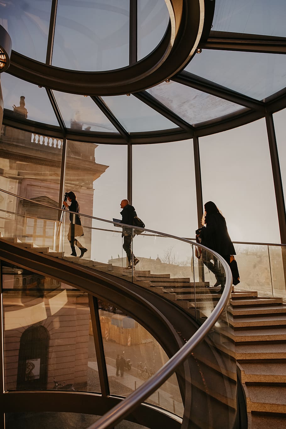 three women walking upstairs at the glass building, handrail