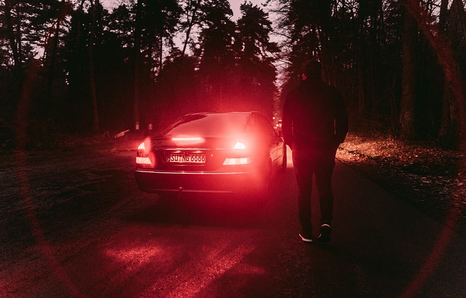 person standing near black car, light, road, tree, forest, woodland