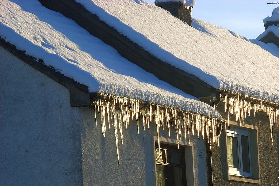 Icicles overhanging from a snow-covered roof in Scotland, ice