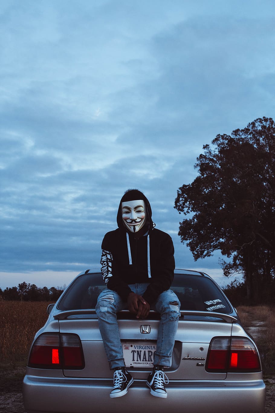 Man Wearing Guy Fawkes Mask While Sitting on Silver Honda Civic