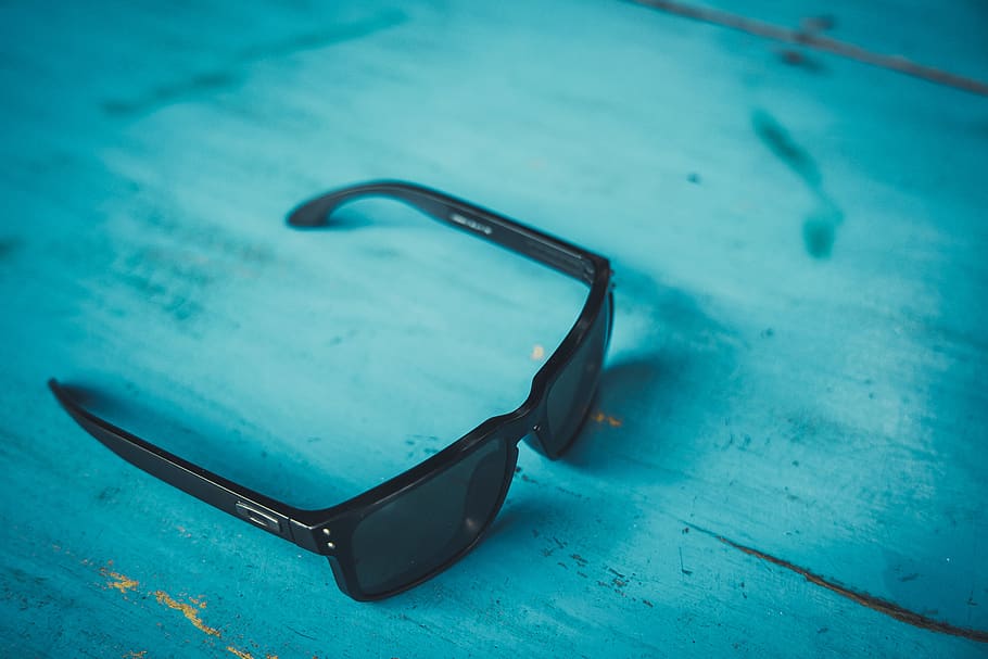 black framed black lens sunglasses on blue surface, accessory