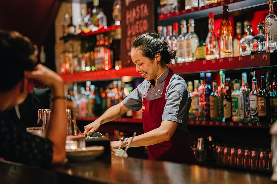 Woman Bartender Smiling While Mixing Liqueurs, alcohol, apron
