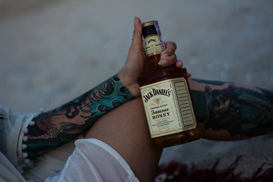 person holding Jack Daniel's whisky bottle, alcohol, drink, beverage