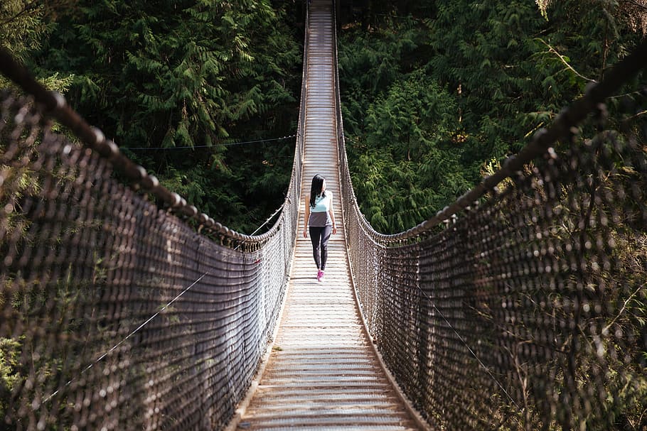 A young Asian woman walking on a suspension bridge, 20-25 year old