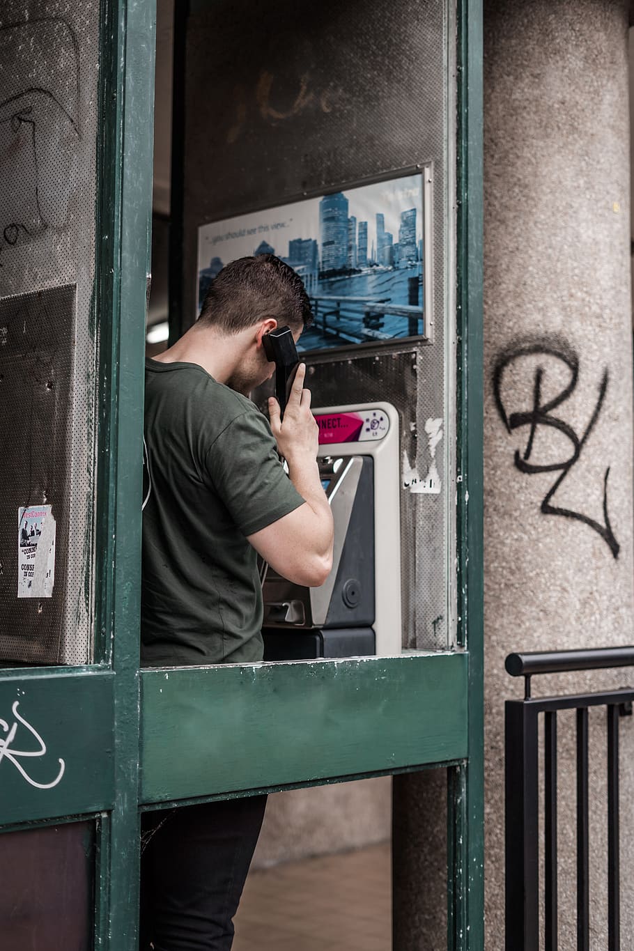 man standing while using telephone, person, human, railing, graffiti