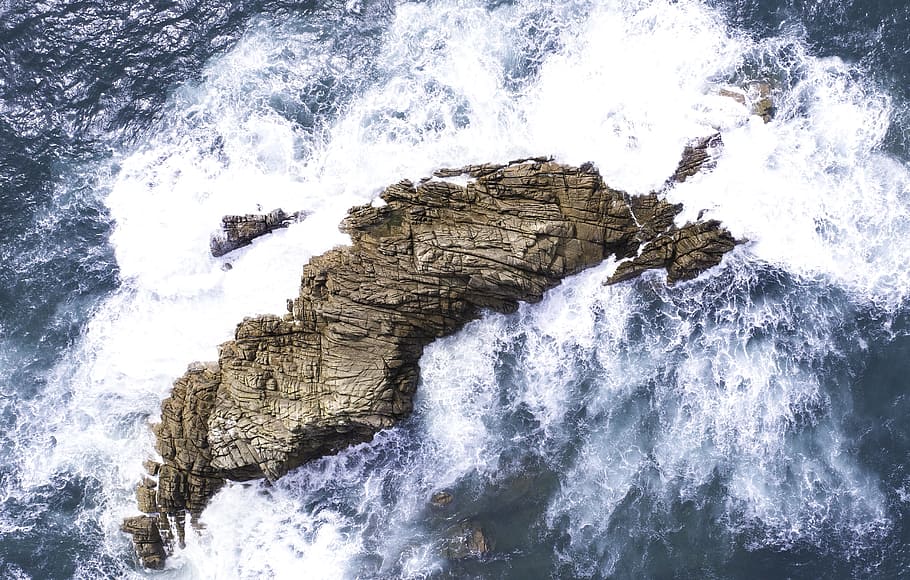 waves crashing on rock formation, drone view, aerial view, island