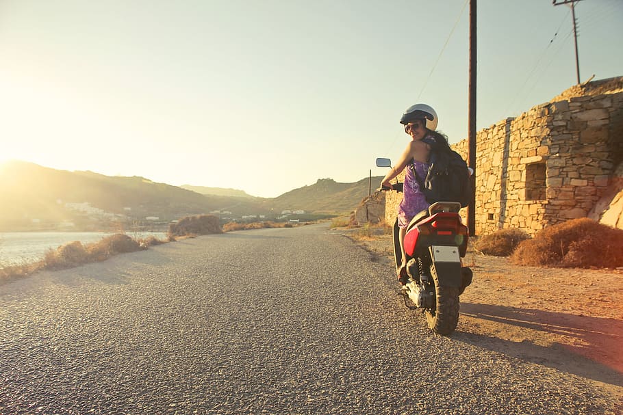 Yoing Girl in sunglasses riding a motorcycle and looking back on a Asphalt Road during early morning