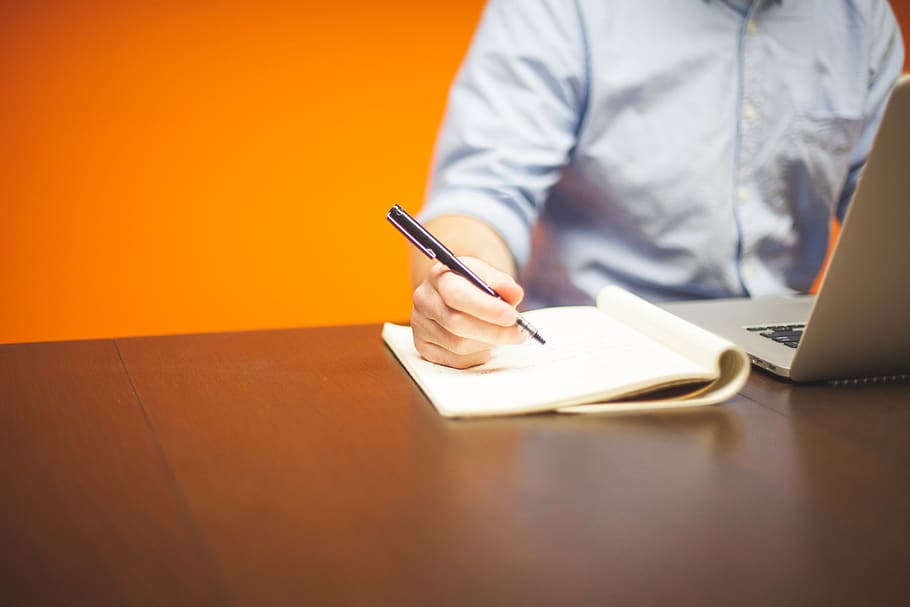 Person Writing on Note Beside Gray Laptop Computer, desk, guy HD wallpaper