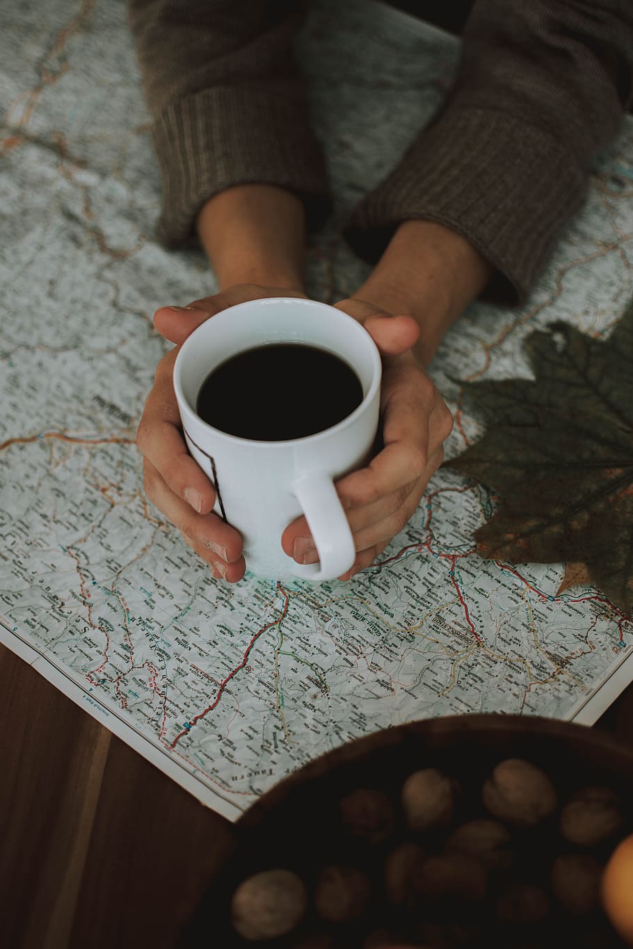 white ceramic mug filled with black liquid, map, holding, cup